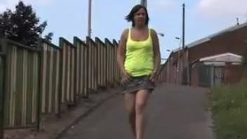 Young woman in a yellow tee urinates against the wall