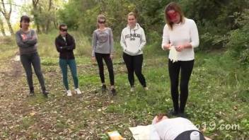 Five youthful females defecate into the mouth of a mature male outdoors