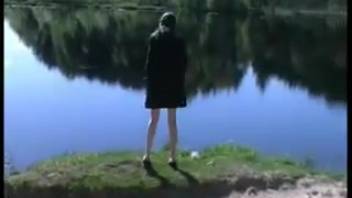 Slender dark-haired woman peeing on a sandy shore