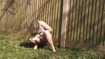 Girl in a white skirt pees by the fence