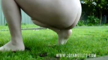 Young woman defecating on the lush green grass